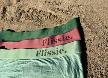 Folded pairs of Flissie bamboo viscose boxer shorts on a beach background