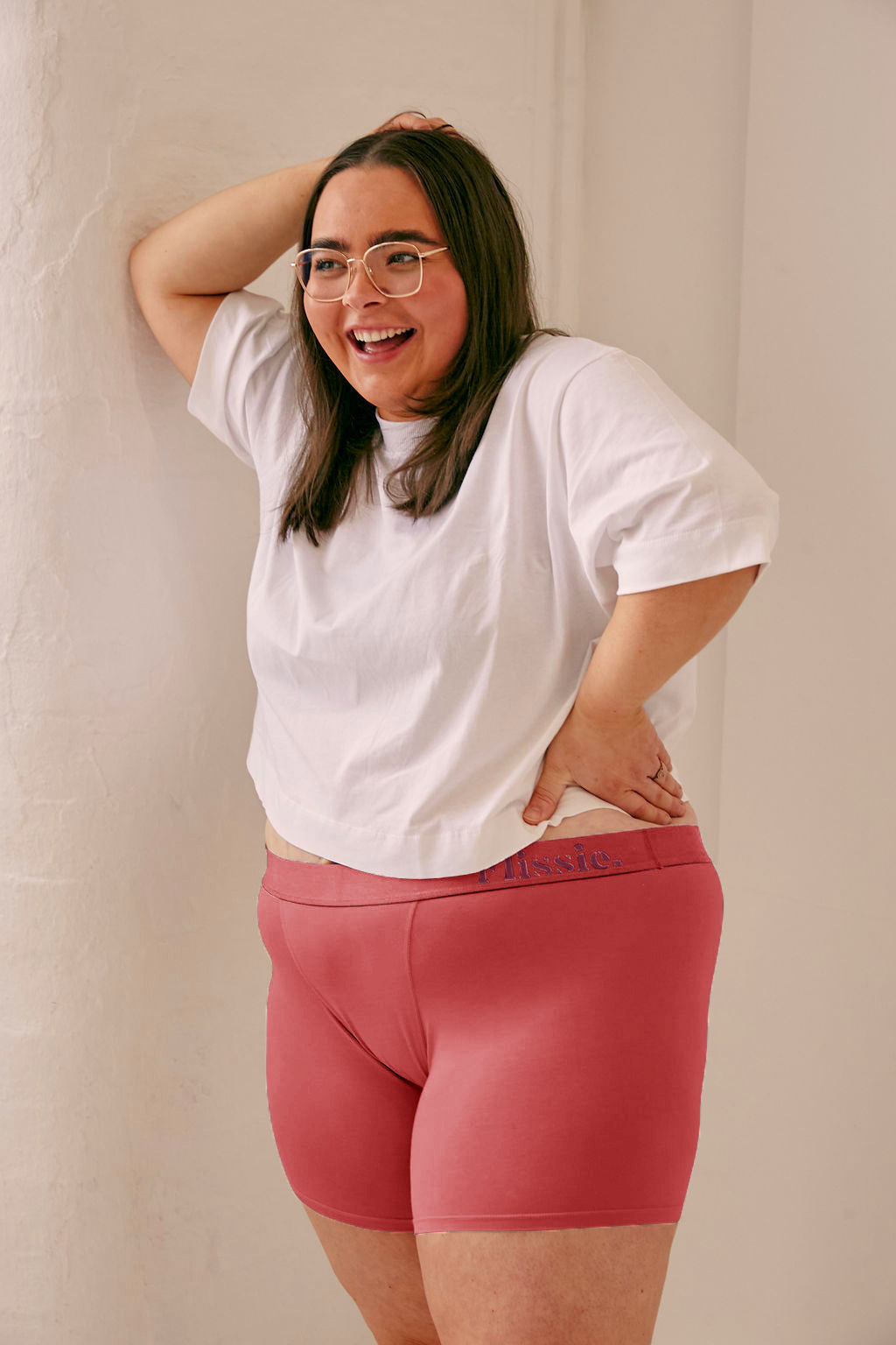 Model in glasses wearing Flissie women's bamboo boxer shorts in plum pink with a white T-shirt
